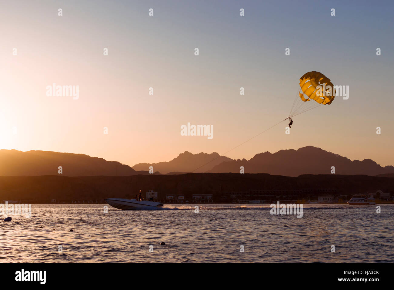 SHARM EL SHEIKH, EGYPT - FEBRUARY 28, 2014: Parachuting over a sea, towing by a boat: happy people is flying on a parachute Stock Photo