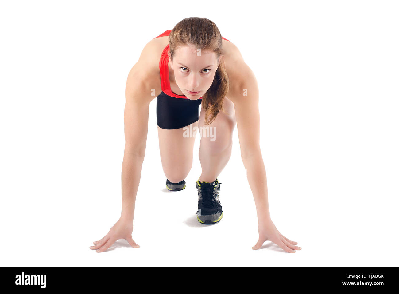 Young athletic woman in crouched starting position ready to start race. Isolated on white background. Stock Photo