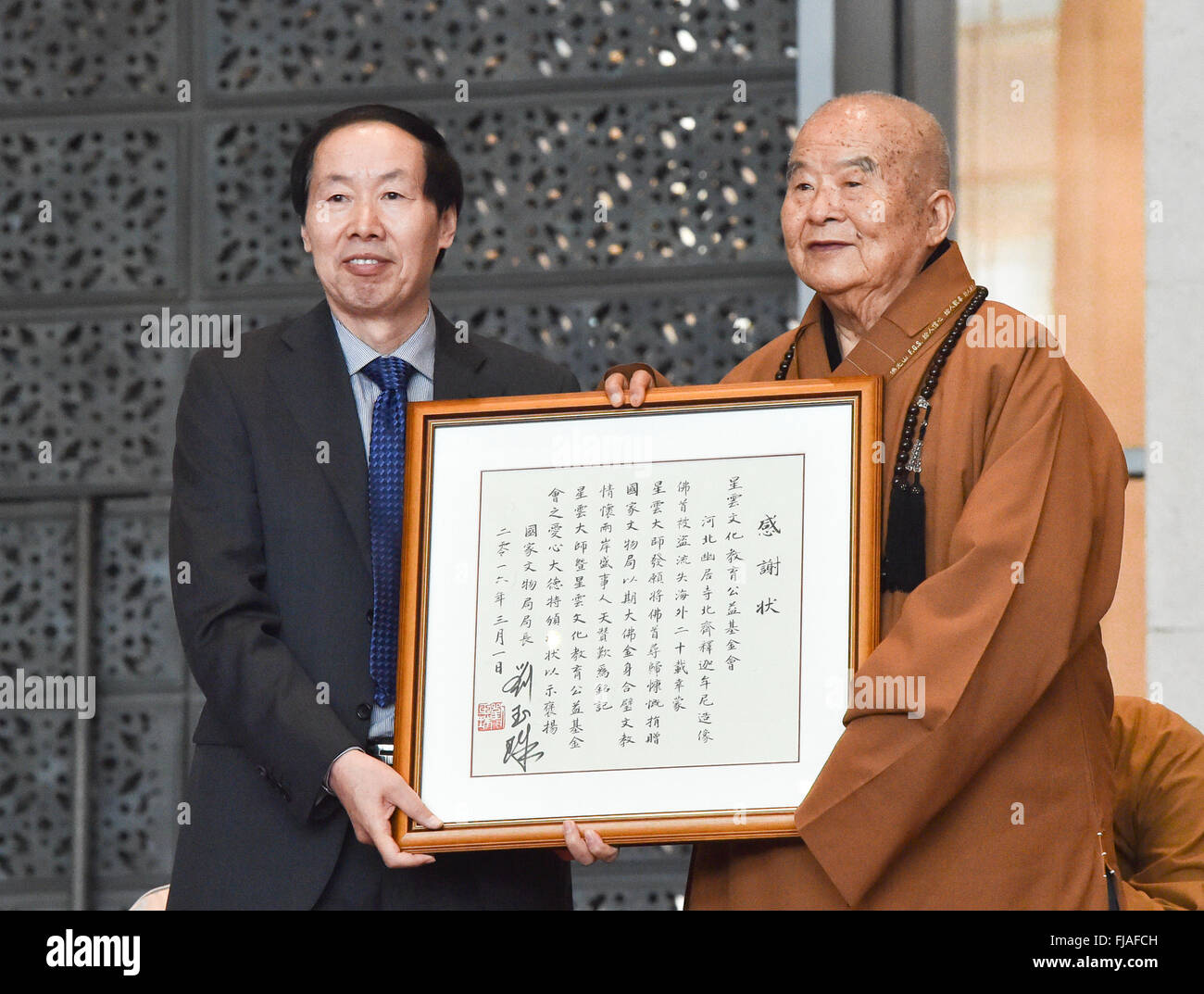 (160301) -- BEIJING, March 1, 2016 (Xinhua) -- Liu Yuzhu (L), head of the State Administration of Cultural Heritage, presents a certificate of appreciation to Master Hsing Yun, for his returning of a head of an ancient Buddha statue of the North Qi dynasty during a ceremony in Beijing, capital of China, March 1, 2016. The white marble Buddha statue, which was made around 556, was originally worshipped at Youju Temple in north China's Hebei Province, where the Buddha's head was stolen in 1996. Master Hsing Yun, founder of Fo Guang Shan Monastery in Taiwan, decided to return the 80 kg statue hea Stock Photo