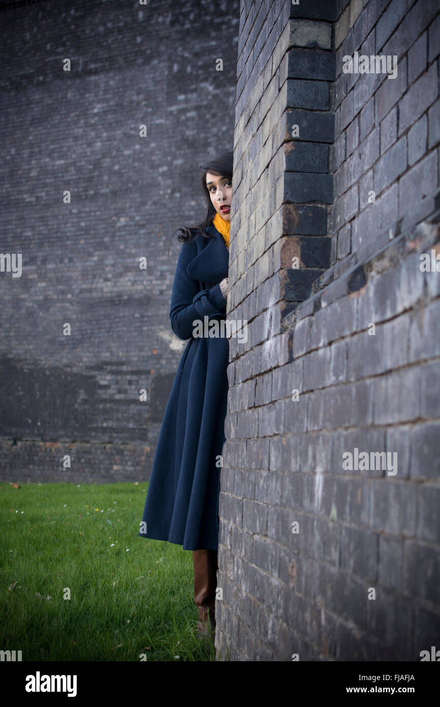 Woman hiding behind a wall Stock Photo