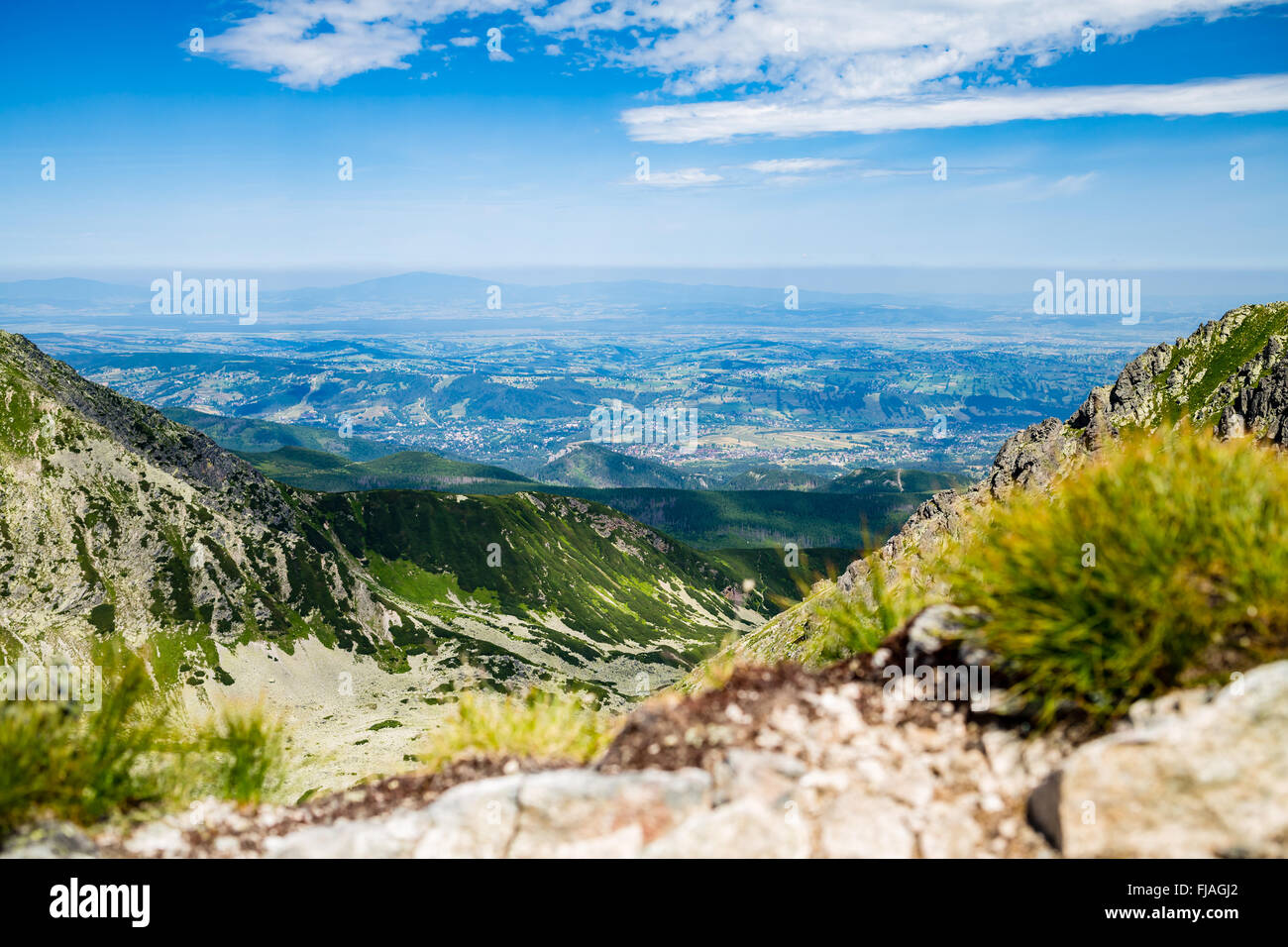 Inspiring Mountains Landscape View, sunny day in summer Tatras. Looking at town, green valley from mountain ridge over blue sky Stock Photo
