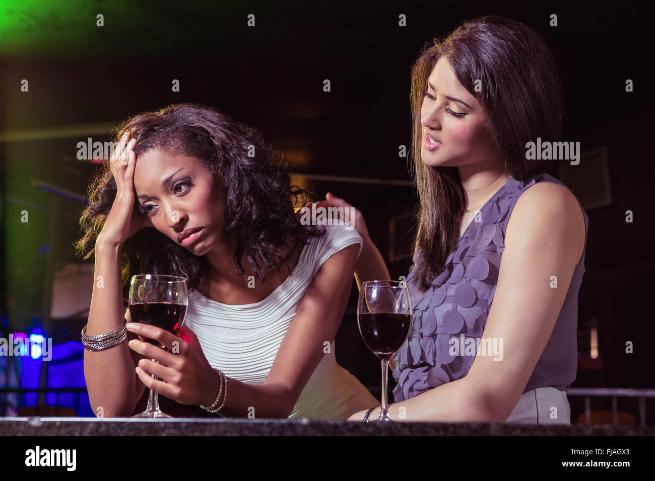 Woman having drinks and comforting her depressed friend Stock Photo