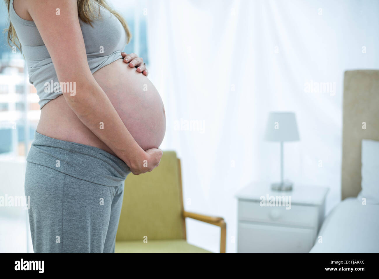 Pregnant woman holding her stomach Stock Photo - Alamy