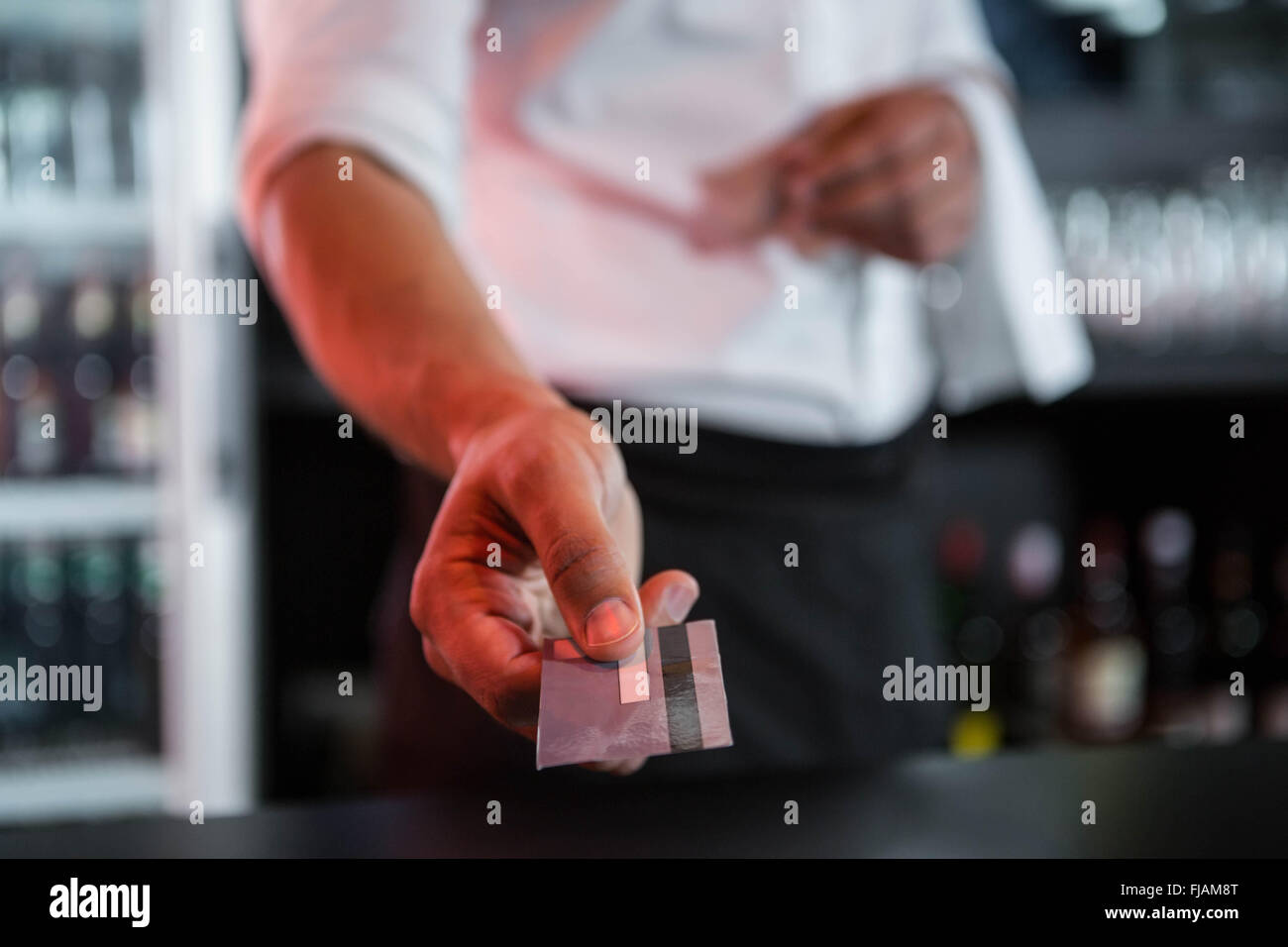 Bartender accepting a credit card at bar counter Stock Photo