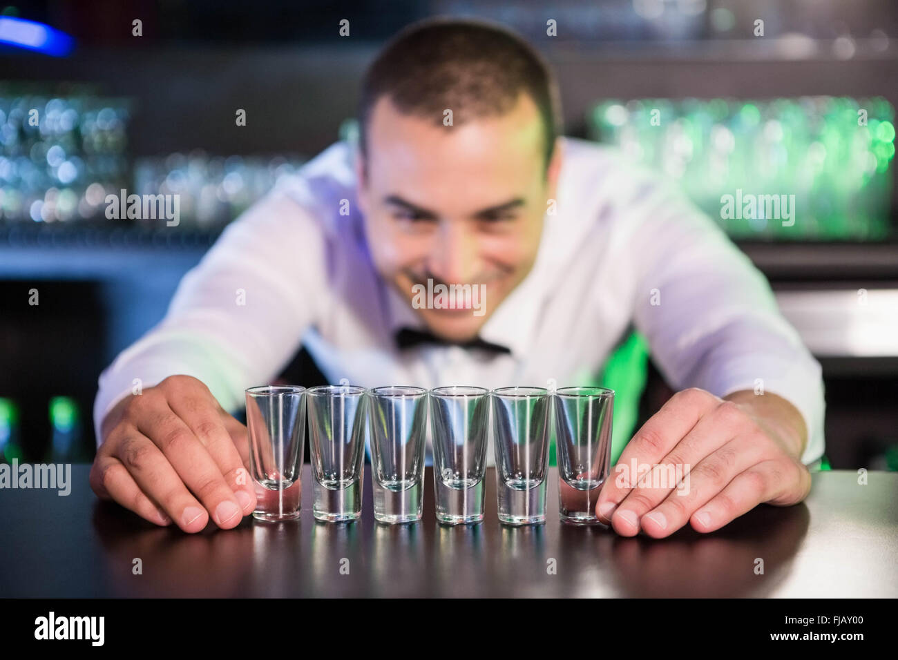Bartender placing shot glasses on bar counter Stock Photo