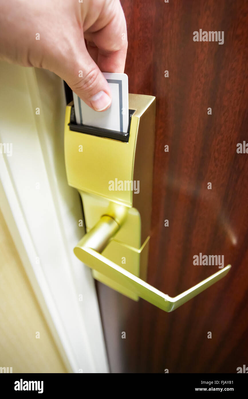 Person's hand inserting a keycard into a hotel room electronic door lock to unlock the door Stock Photo
