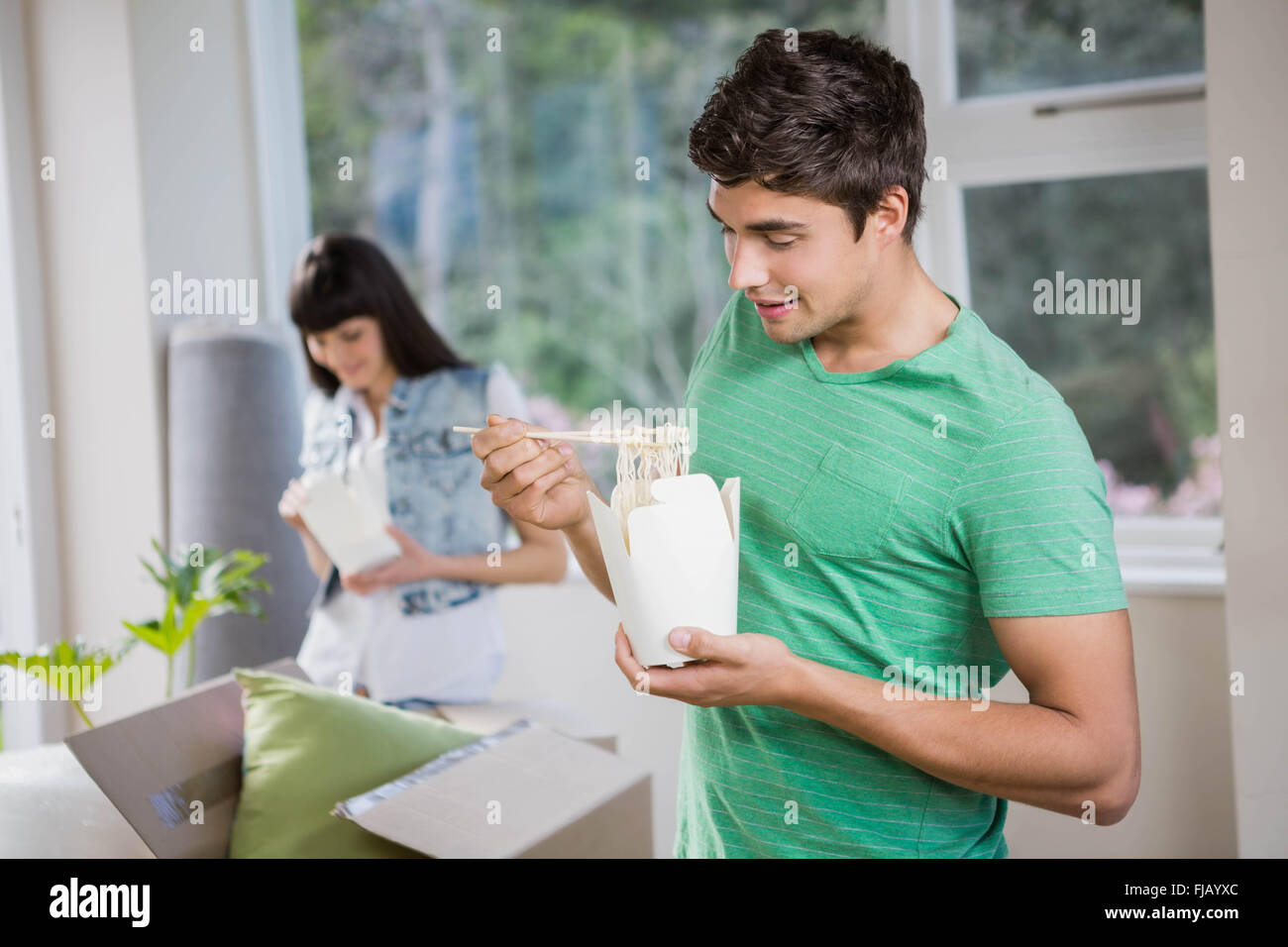 Young man and woman eating noodles at home Stock Photo