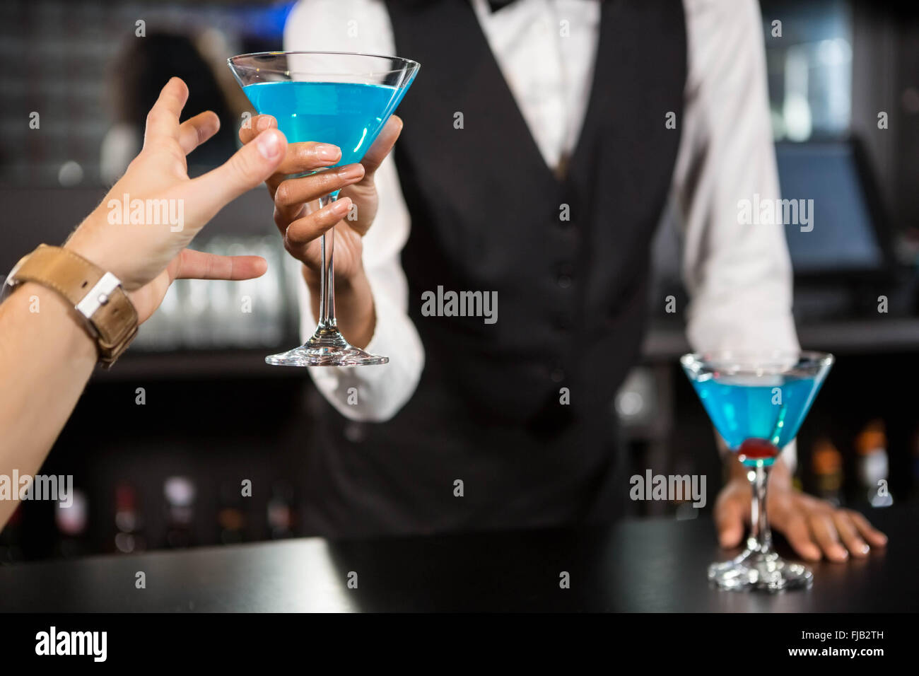 Bartender serving blue cocktail at bar counter Stock Photo