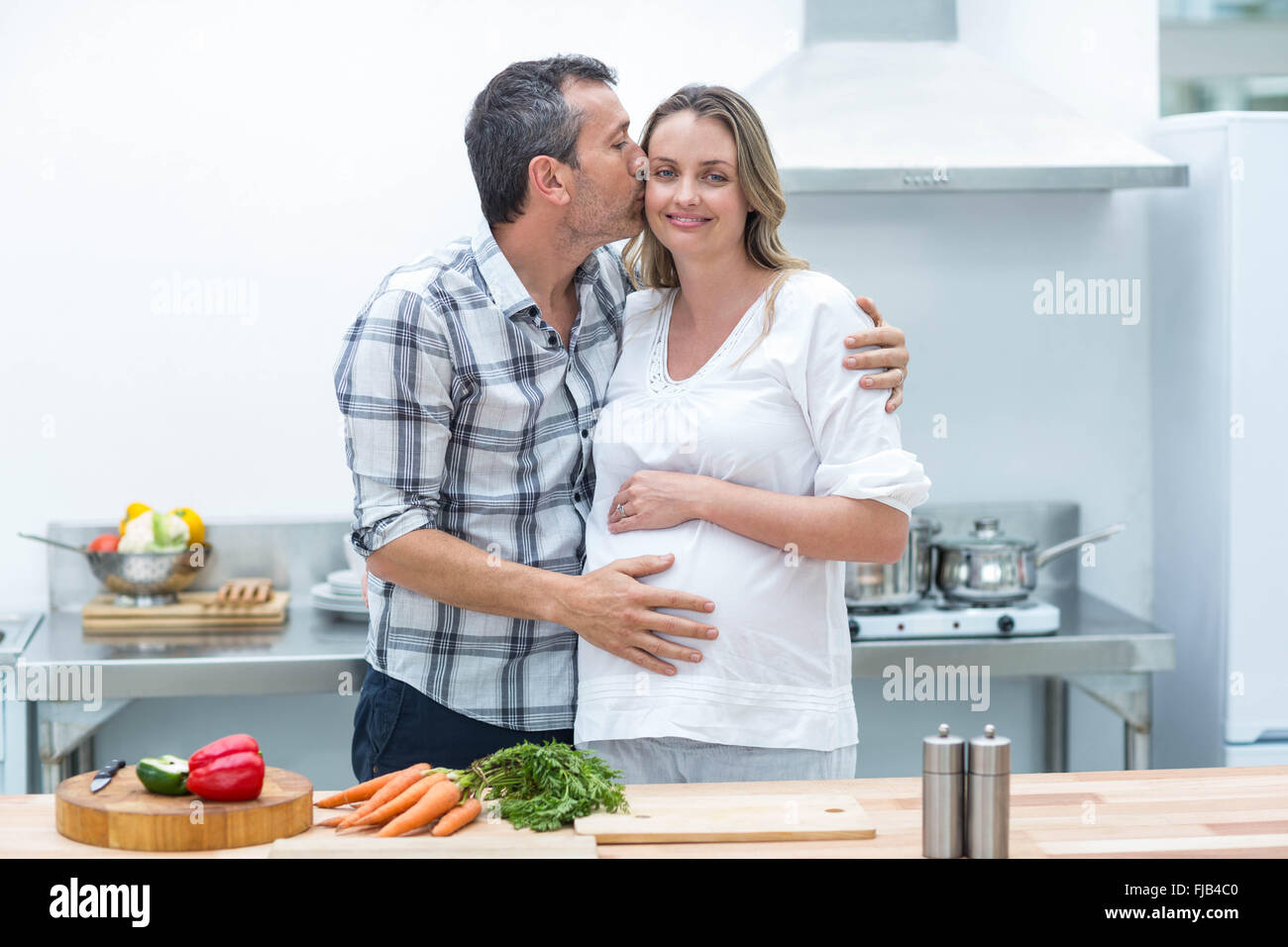 Man kissing on cheek of pregnant woman Stock Photo Alamy