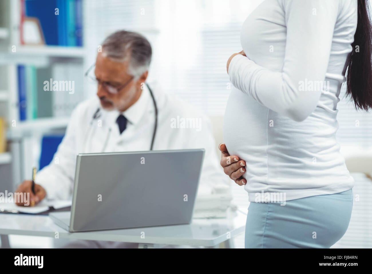 Pregnant woman holding her stomach Stock Photo - Alamy