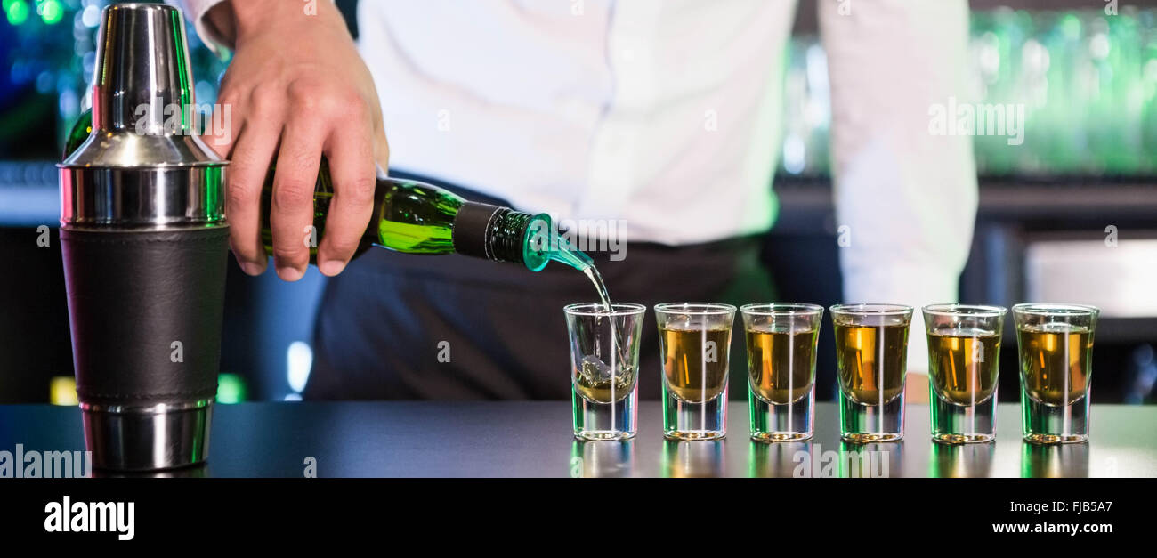 Bartender pouring tequila into shot glasses Stock Photo