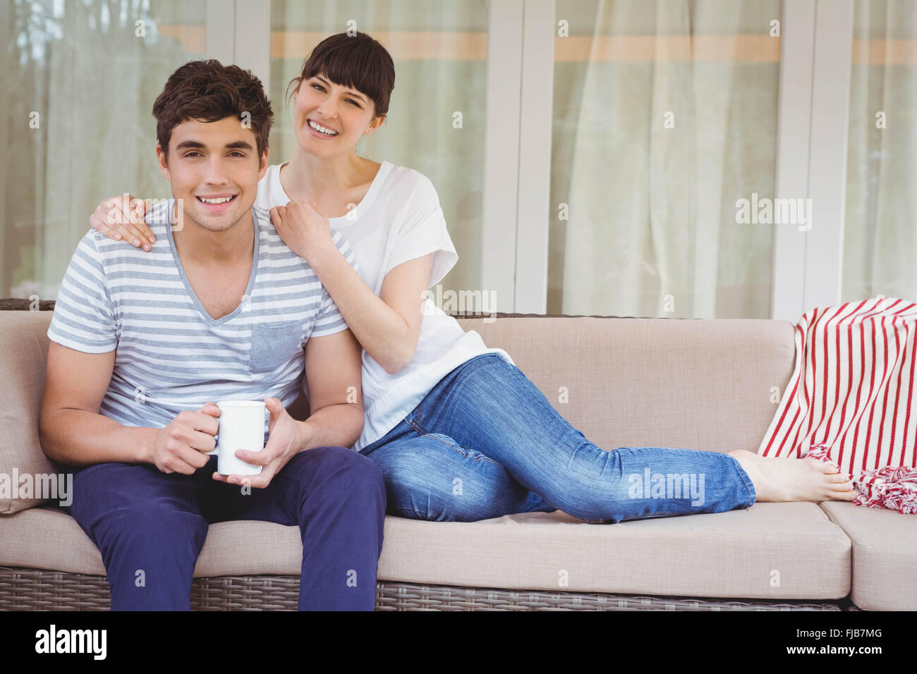 Young couple sitting on sofa Stock Photo - Alamy