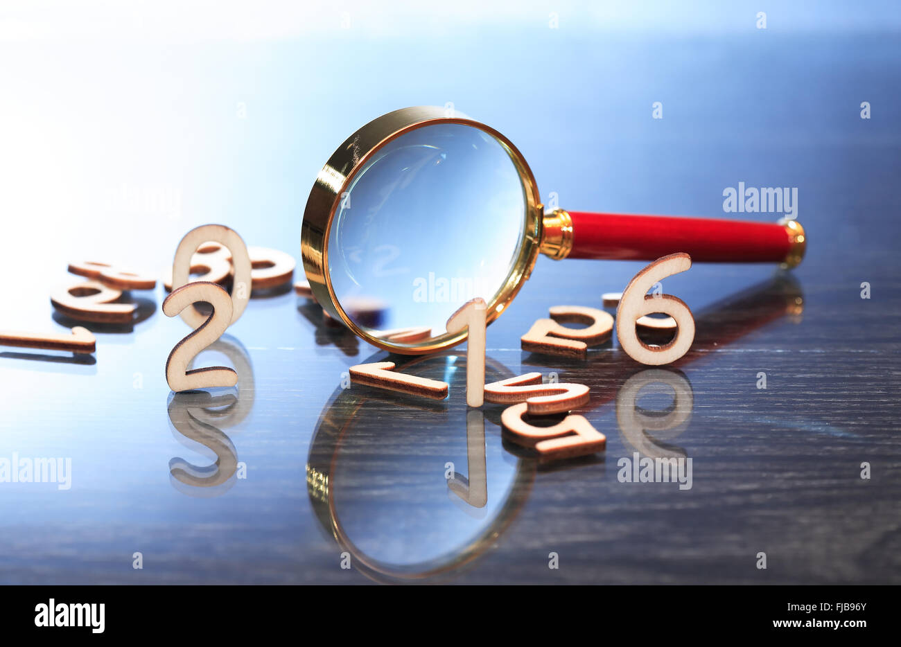 Investigation concept. Magnifying glass near set of wooden digits Stock