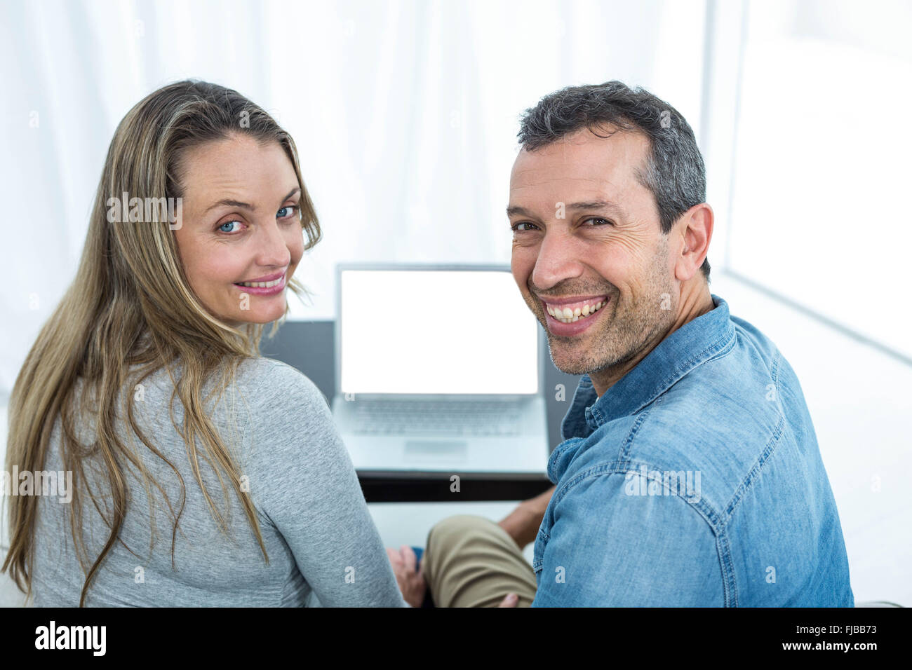 Couple using laptop in living room Stock Photo - Alamy