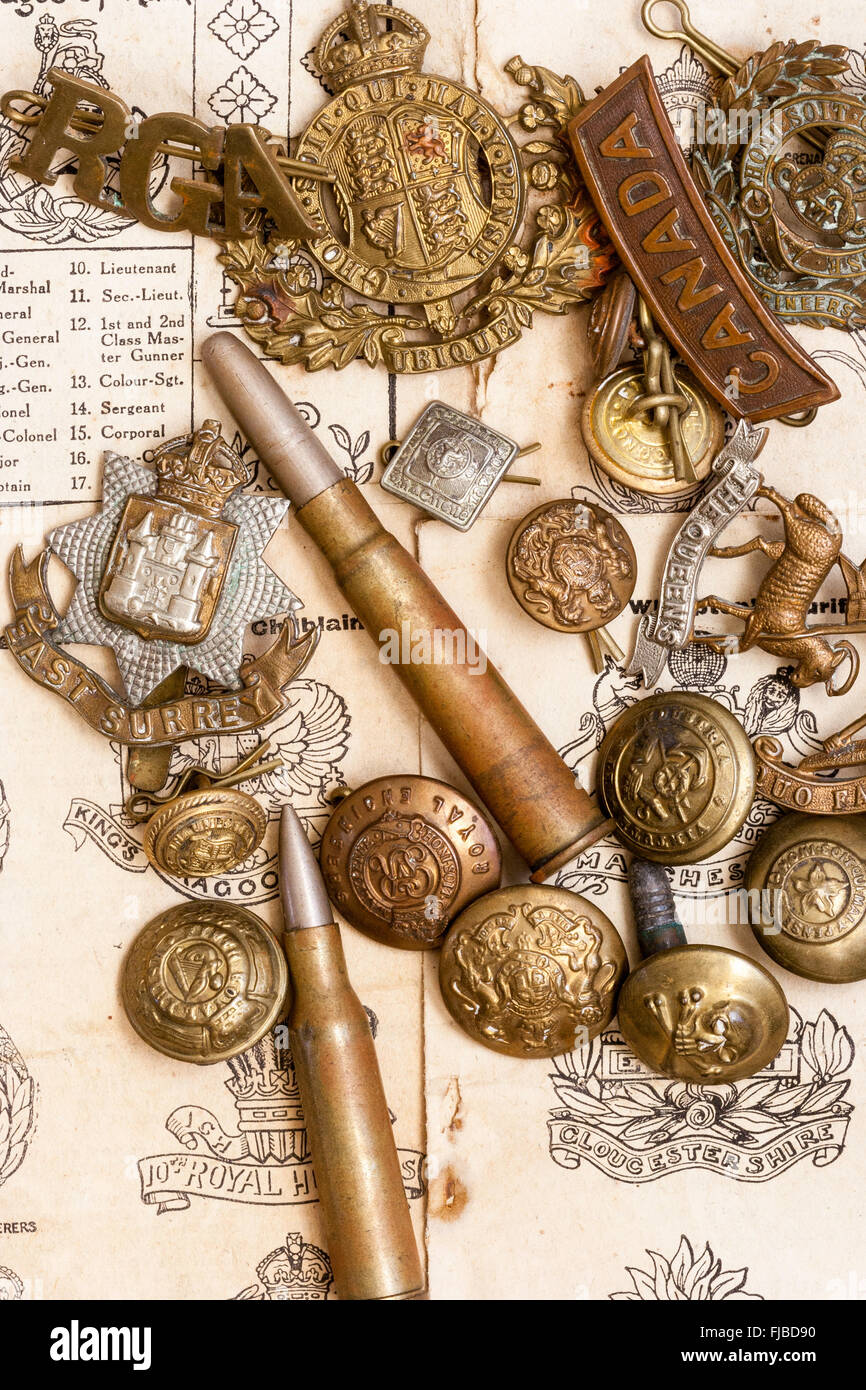 World war one memorabilia. Cap badges, bullets, buttons laid out on first world war booklet page illustrating different British army cap badges. Stock Photo