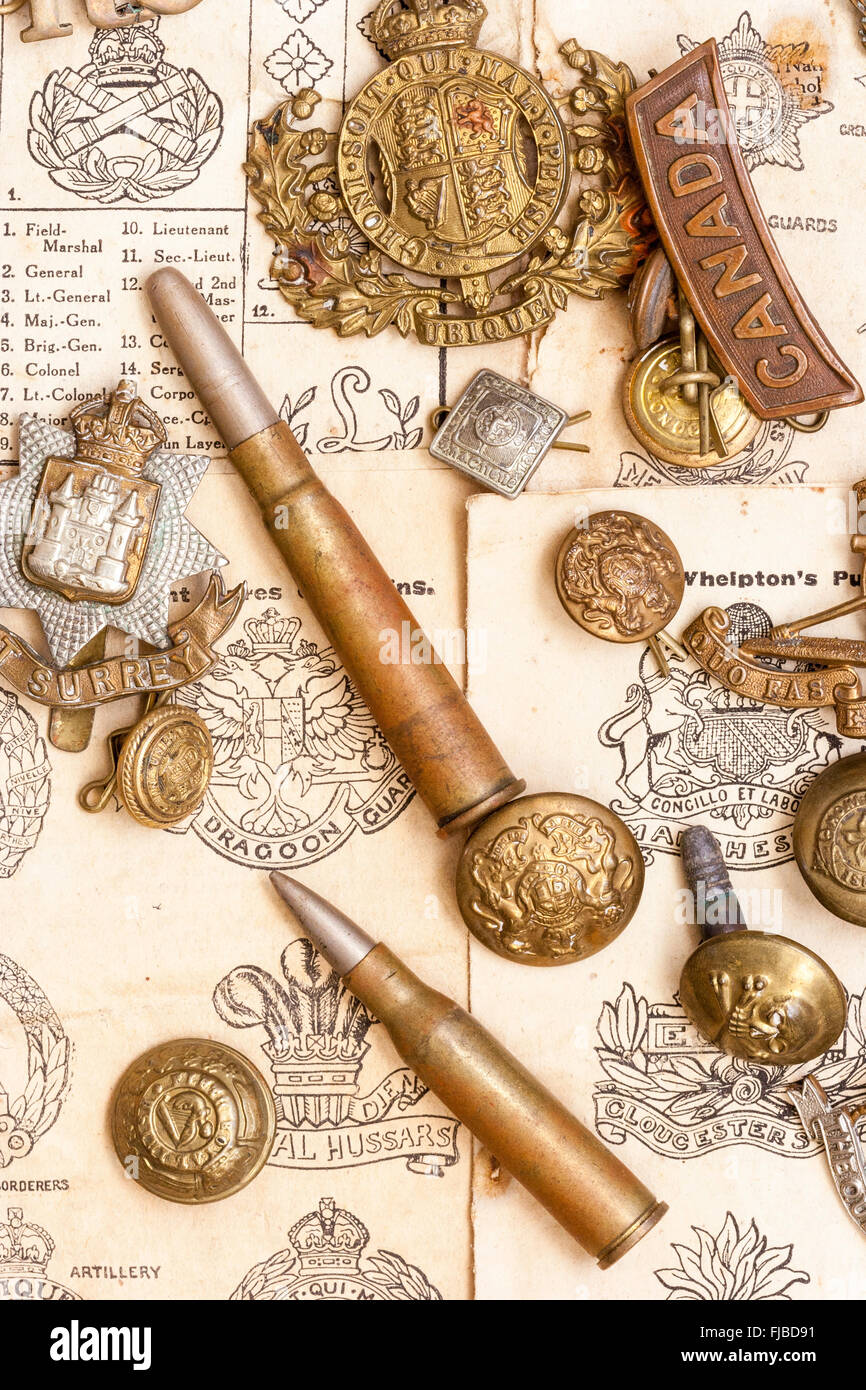 World war one memorabilia. Cap badges, bullets, buttons laid out on first world war booklet page illustrating different British army cap badges. Stock Photo
