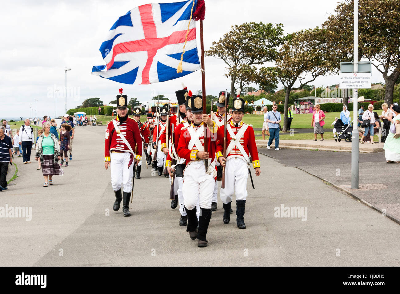 Napoleonic wars re-enactment. British Redcoats, 1st foot regiment, Grenadier Guards, marching towards viewer in column with Union Jack flag flying. Stock Photo