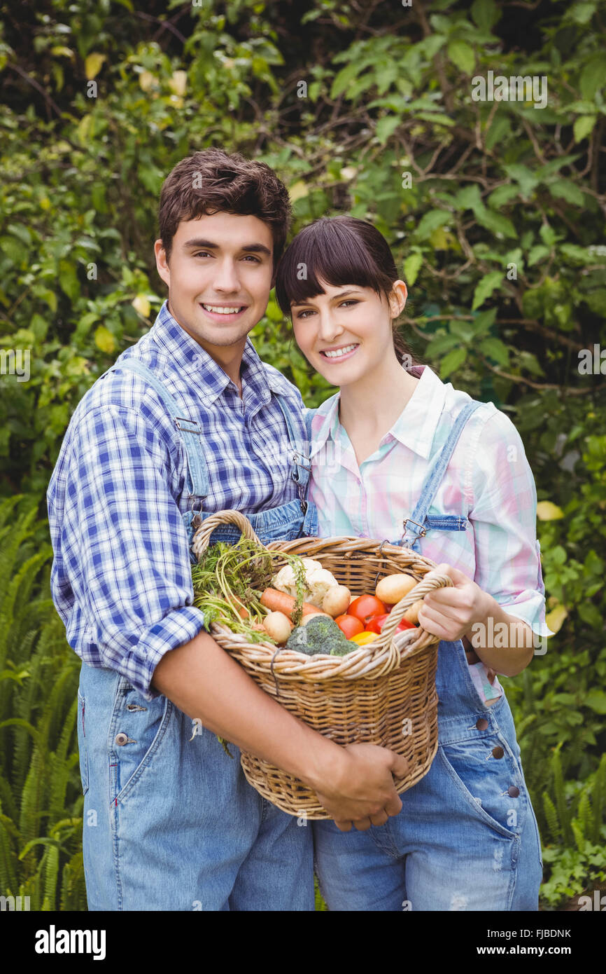 Young couple holding a basket of freshly harvested vegetables Stock Photo