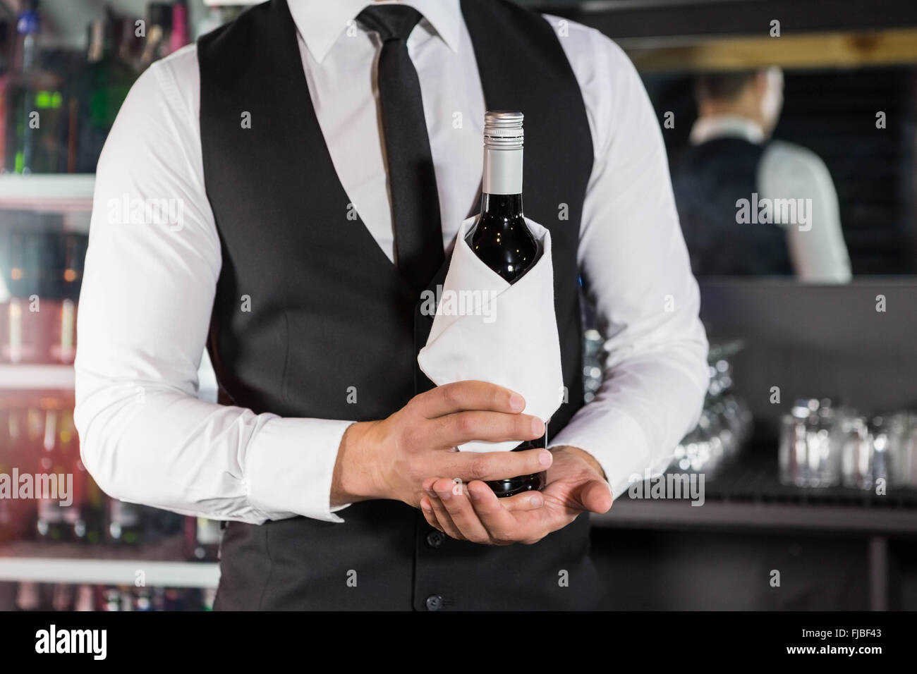 Mid section of bartender holding a wine bottle Stock Photo