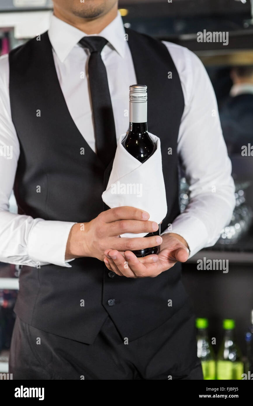 Mid section of bartender holding a wine bottle Stock Photo