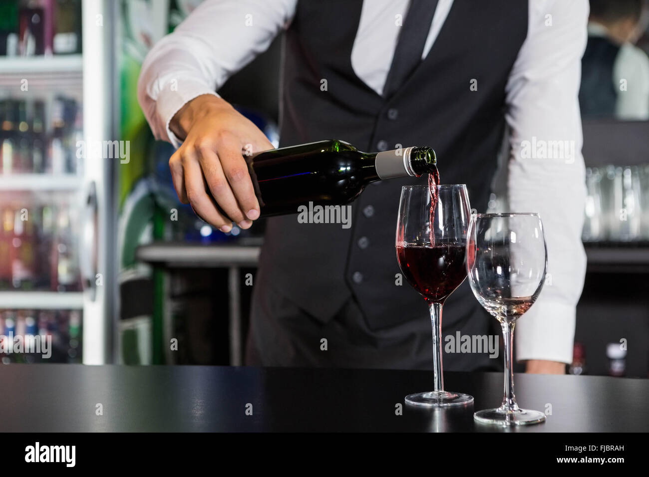 Mid section of bartender pouring red wine in a glass Stock Photo