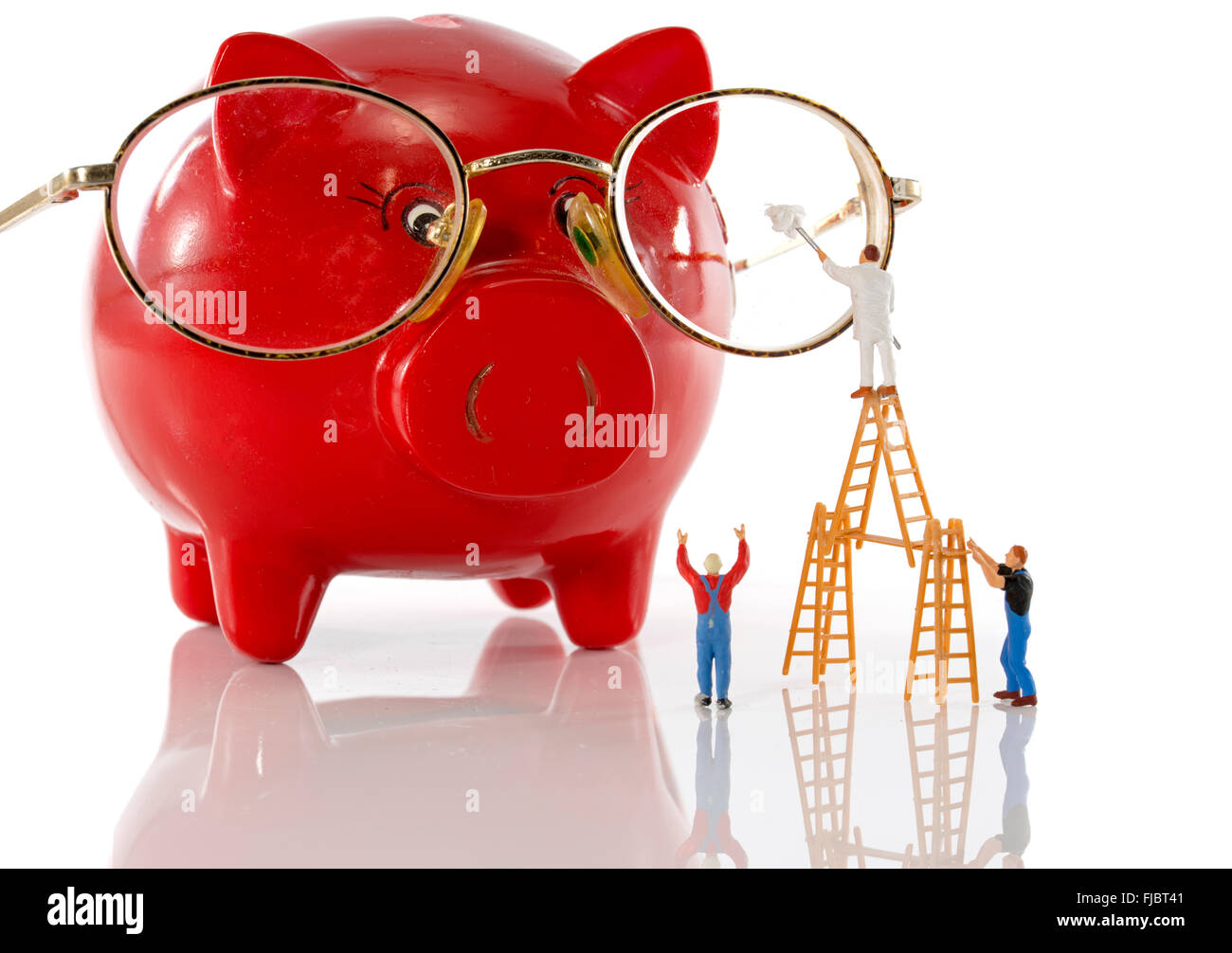 little people puppets standing on scaffold cleaning glasses of piggy bank Stock Photo