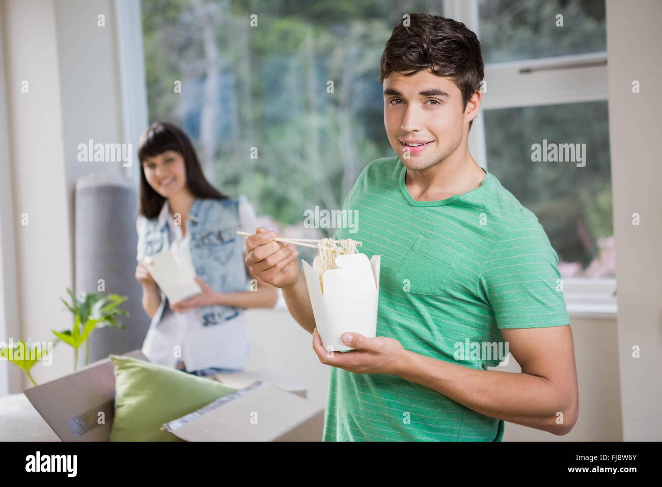 Young man and woman eating noodles at home Stock Photo