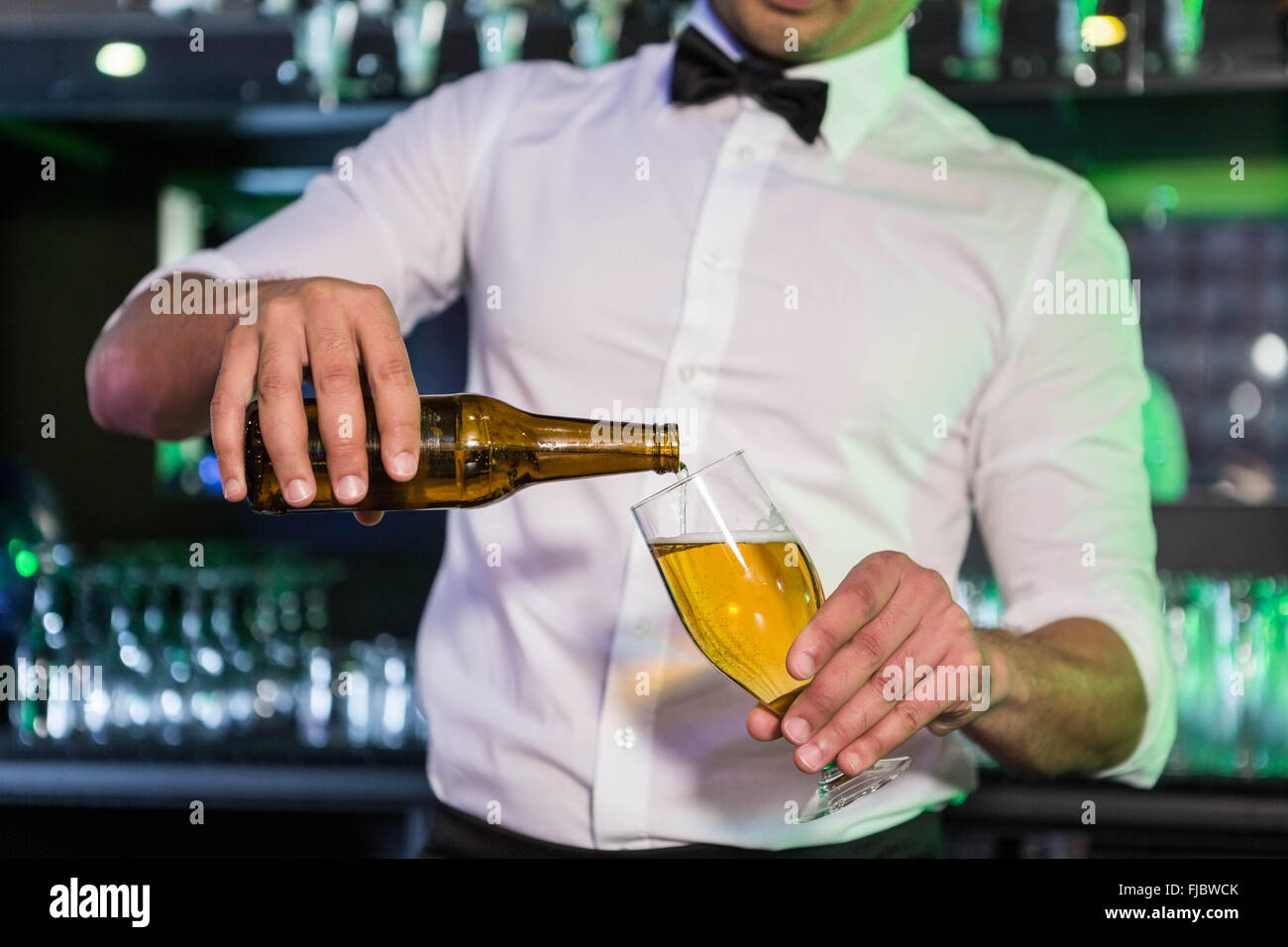 Mid section of bartender pouring beer in a glass Stock Photo
