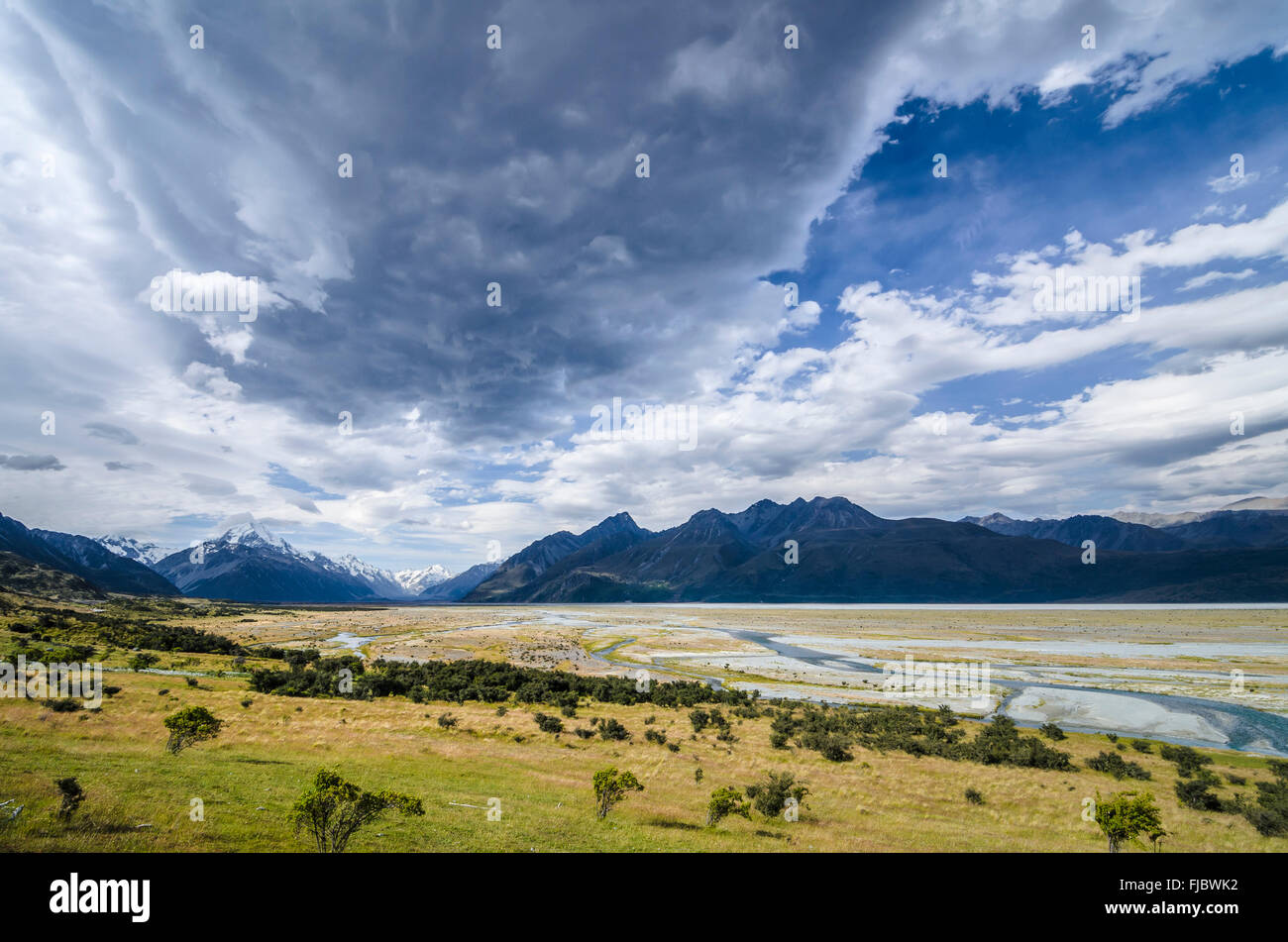 Grassland in front of the wide riverbed of the Tasman River, dramatic clouds, Mount Cook National Park, Pukaki Stock Photo