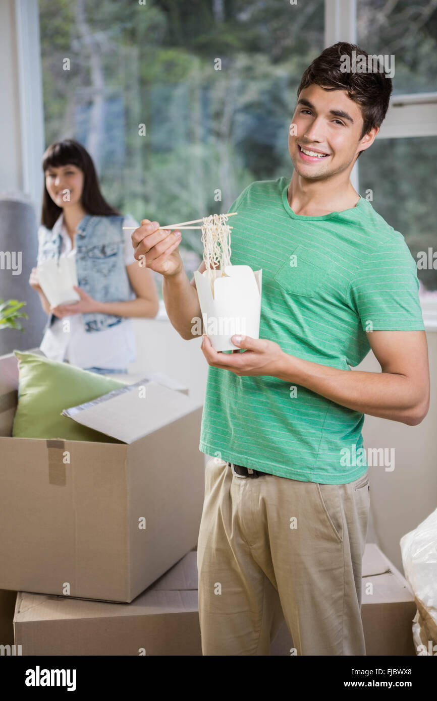 Young man and woman eating noodles at home Stock Photo