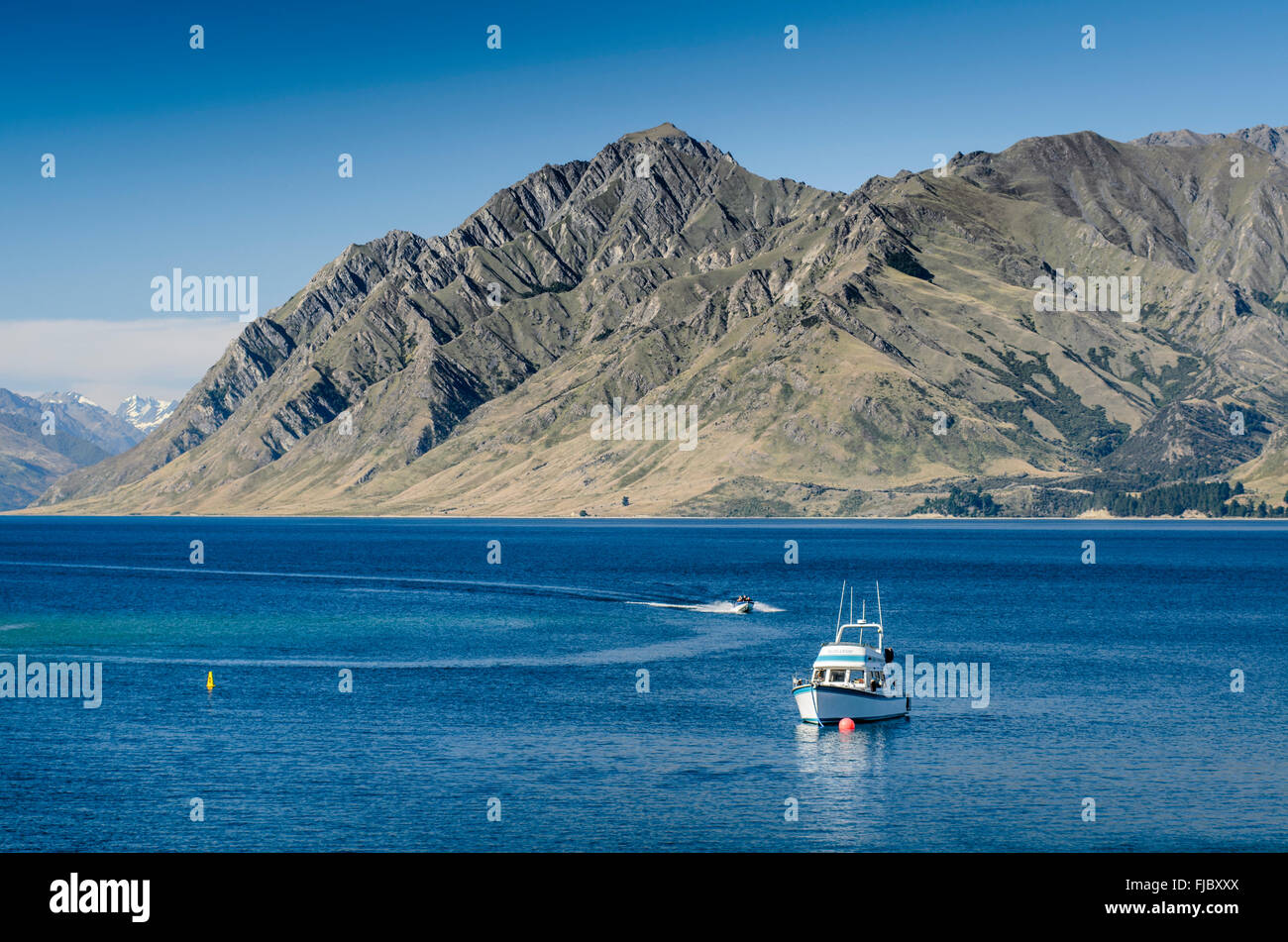 Motorboats on lake Lake Hawea under blue sky, Dingle Burn Mountain in the  back, Otago, New Zealand Stock Photo - Alamy