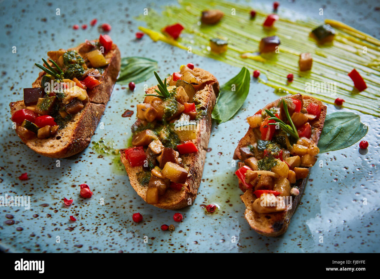 Vegan food: bruschetta with bell pepper, tomatoes, arugula, thyme and basil Stock Photo