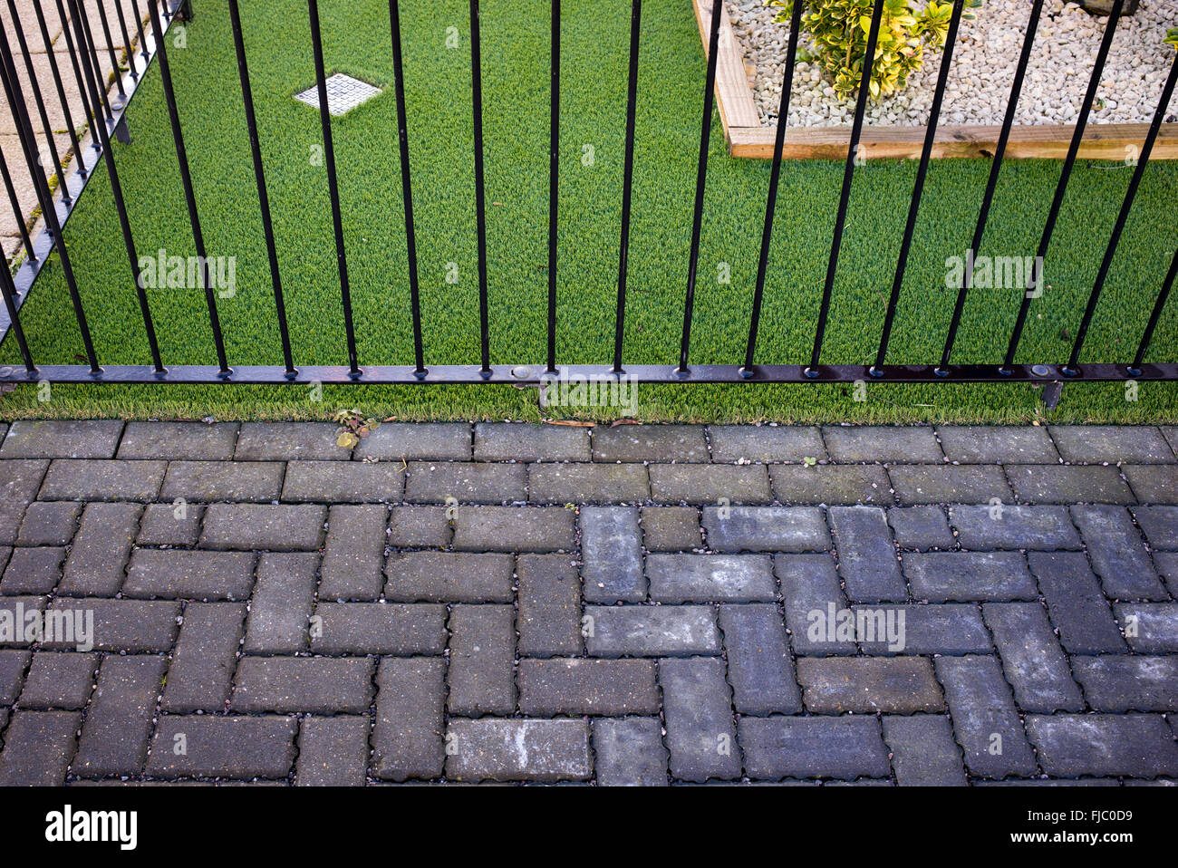 Artificial grass / astro turf meets a paved street path on a new build housing estate. Bicester, Oxfordshire, England Stock Photo