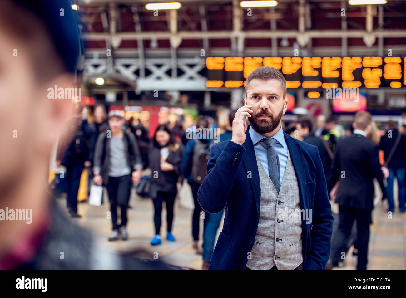 Busy businessman with smartphone, making phone call, crowded sta Stock