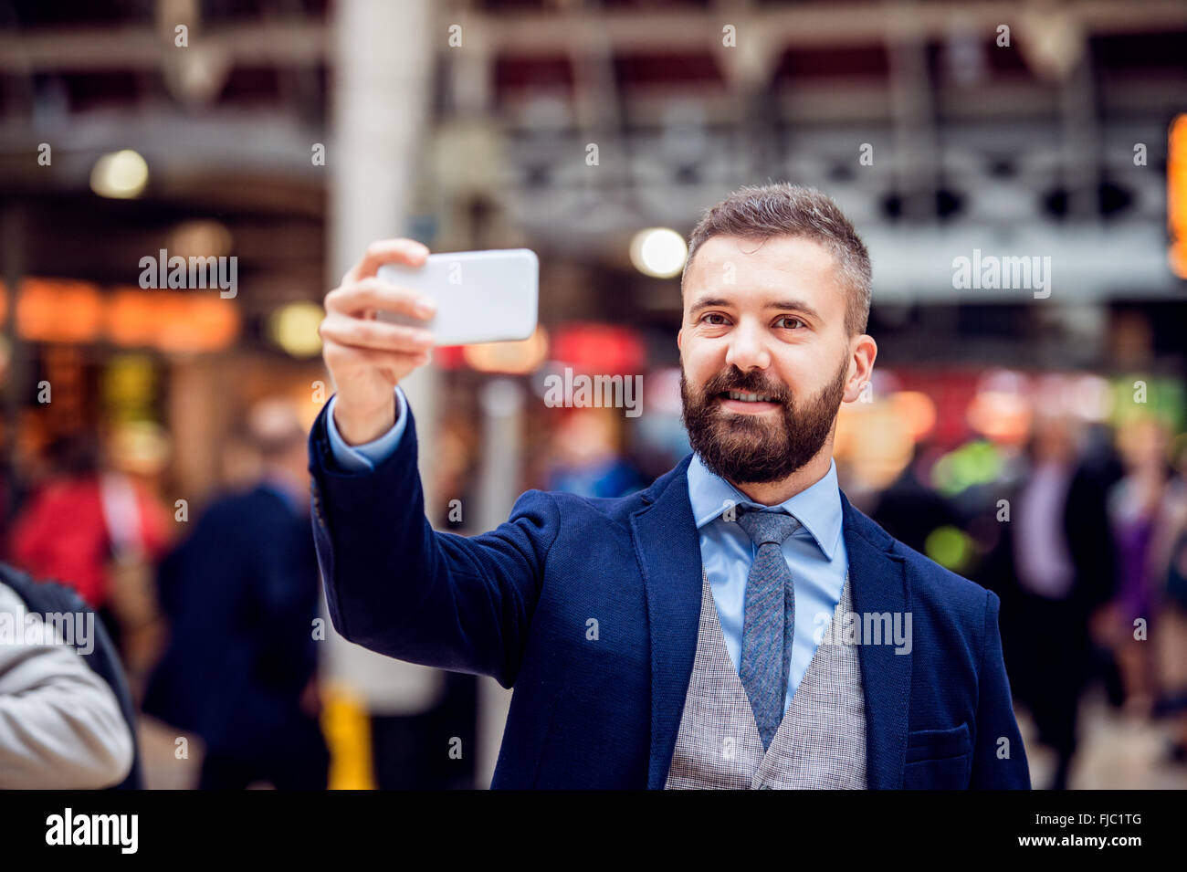 Hipster businessman with smartphone taking selfie, crowded train Stock Photo