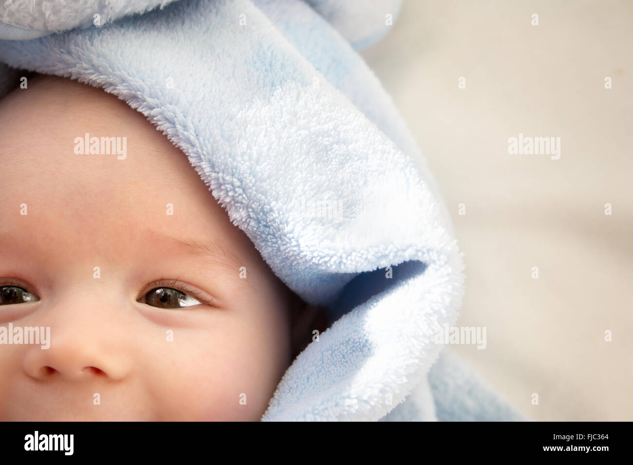 three month old baby wrapped in blue blanket Stock Photo