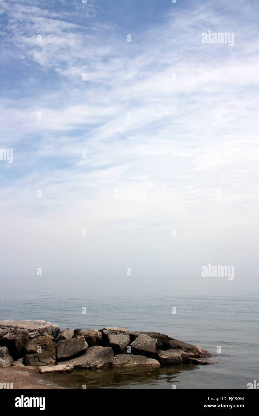 A pile of rocks in front of a great blue sky mostly covered in white ...
