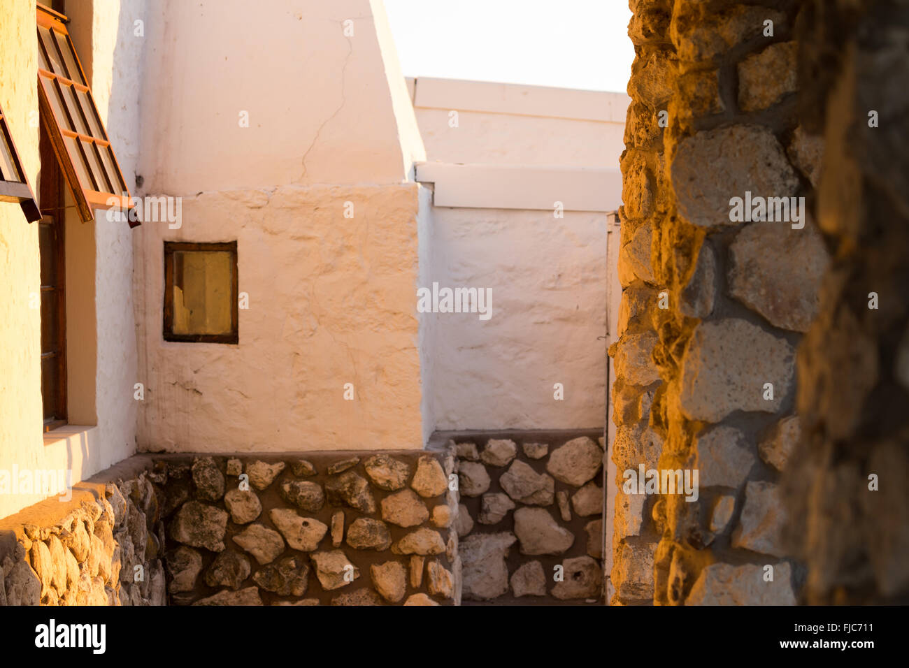 Soft golden light shines through pillars on an old South African farm house veranda. Stock Photo