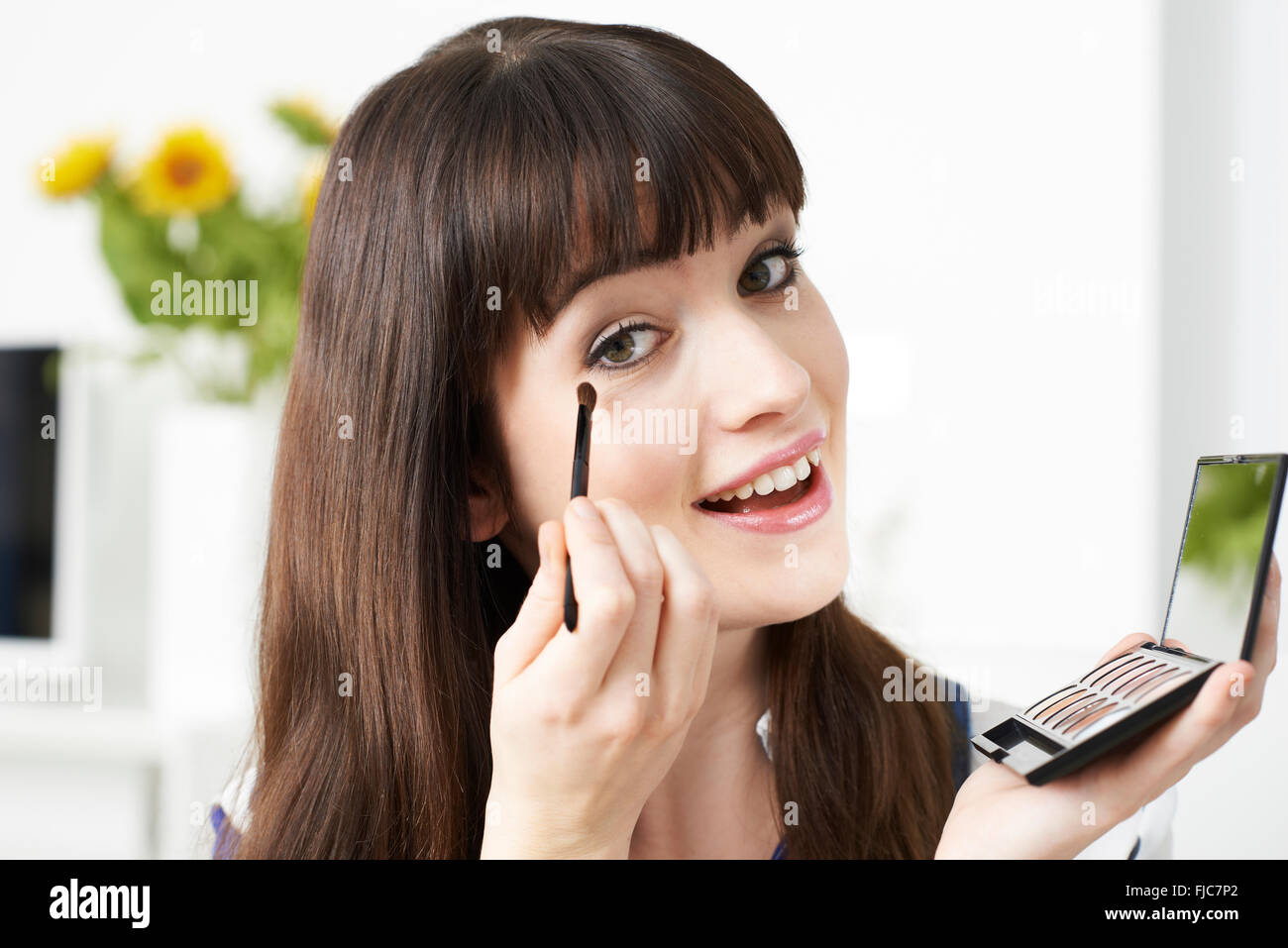 Young Woman Applying Eye Make Up At Home Stock Photo