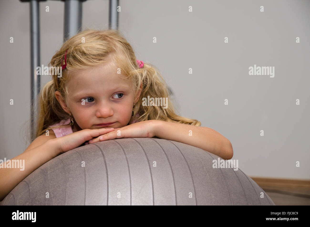 little blond girl in gym with gray fit ball Stock Photo