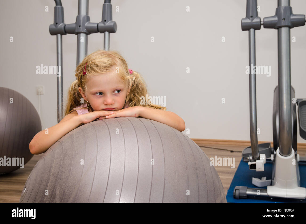 little blond girl in gym with gray fit ball Stock Photo