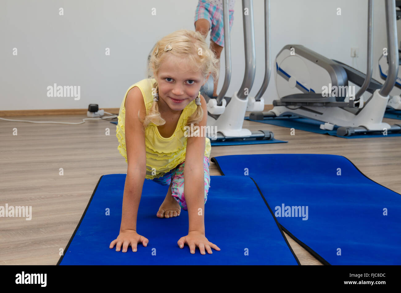 little blond girl in gym doing exercise in blue matt Stock Photo - Alamy