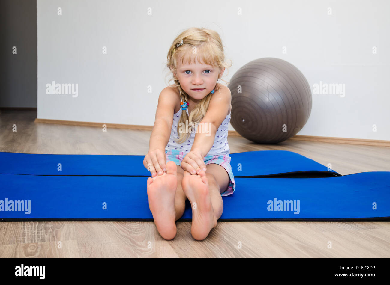 little blond girl in gym doing exercise in blue matt Stock Photo - Alamy
