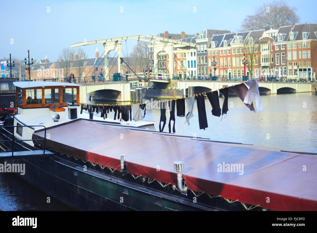 Drying clothes on a barge. Famous Skinny bridge on a background. Amsterdam, Holland Stock Photo
