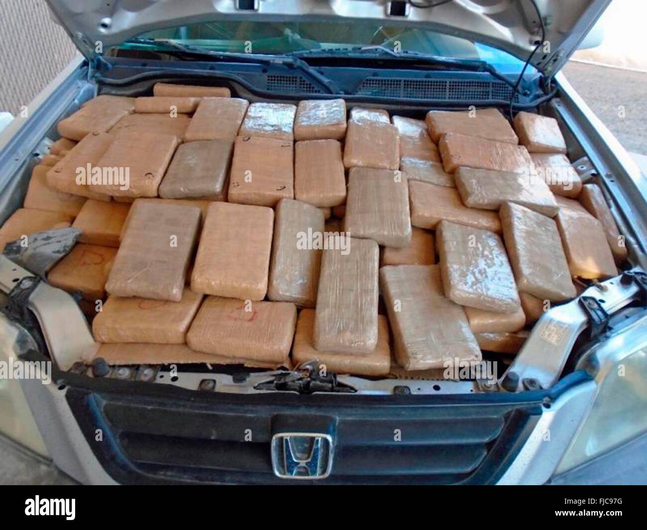 Packages of Marijuana packed into the engine compartment of a vehicle discovered after a U.S Customs and Border Patrol sniffer dog detected the illegal contraband at the Port of Douglas border Crossing January 29, 2016 near Tucson, Arizona. The seizure totaled more than 226 pounds of marijuana worth $113K. Stock Photo
