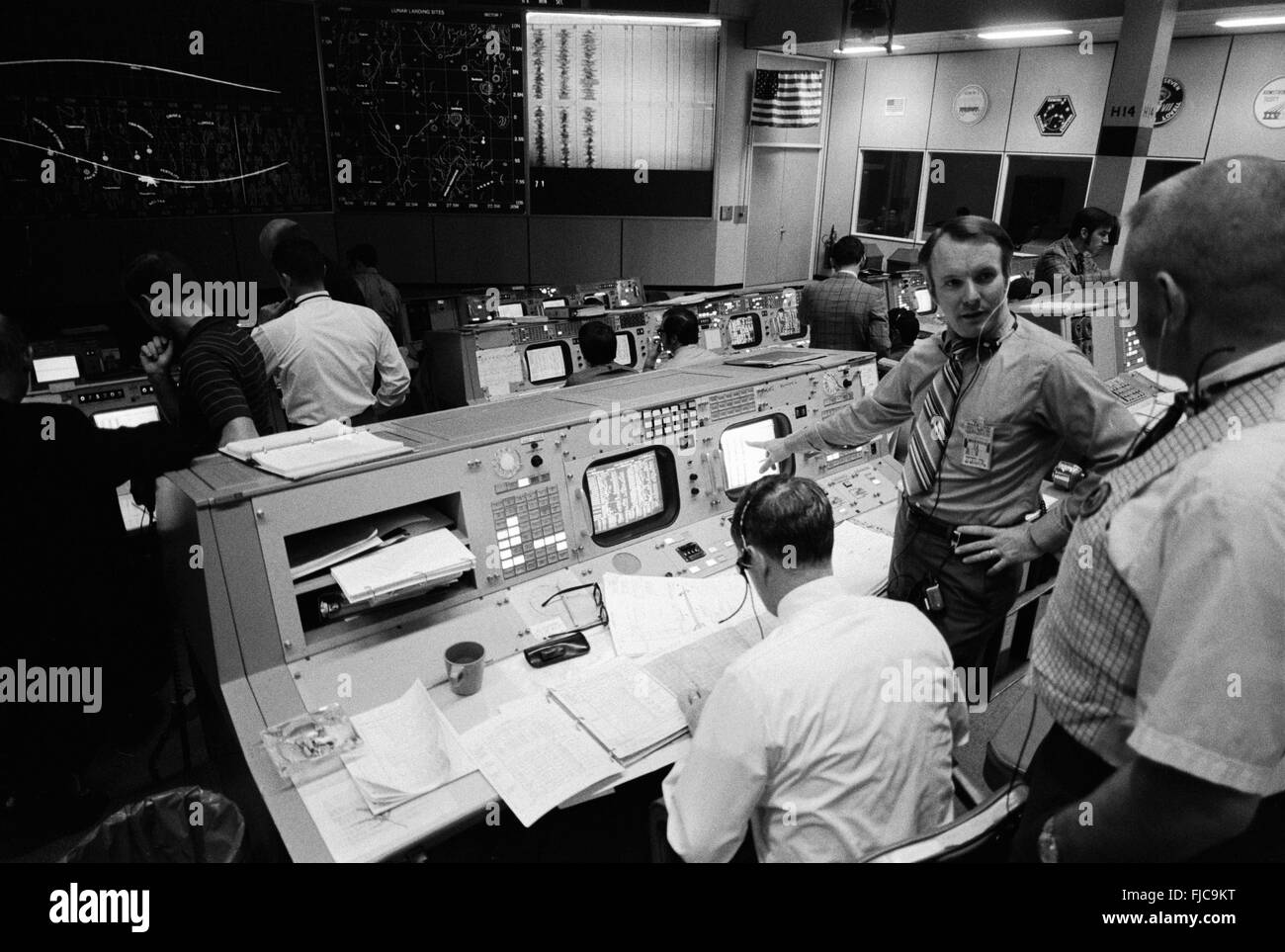 Overall view of activity in the Mission Operations Control Room in the Mission Control Center during the Apollo 14 mission February 4, 1971 in Cape Canaveral, Florida. The flight director's console is in the foreground. Eugene F. Kranz, chief of the MSC Flight Control Division, is in the right foreground. Seated at the console is Glynn S. Lunney, head of the Flight Director Office, Flight Control Division. Facing the camera is Gerald D. Griffin, flight director of the Third (Gold) Team. Stock Photo