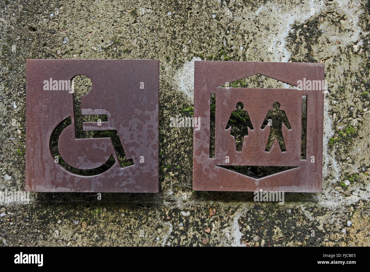 Public and disabled toilets signs cut into rusted metal sheets Stock Photo