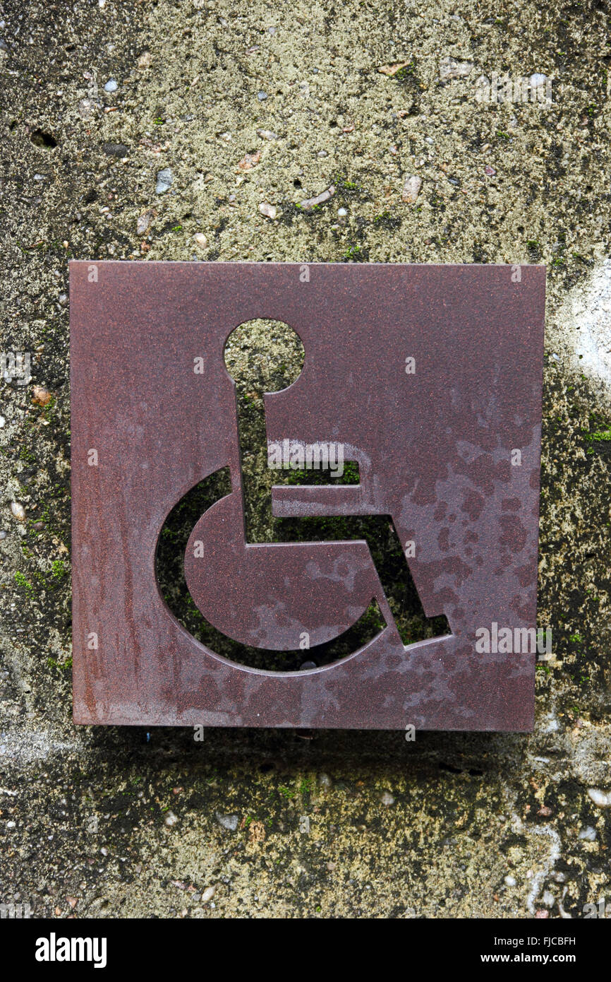 Disabled toilet sign cut into rusted metal sheet Stock Photo