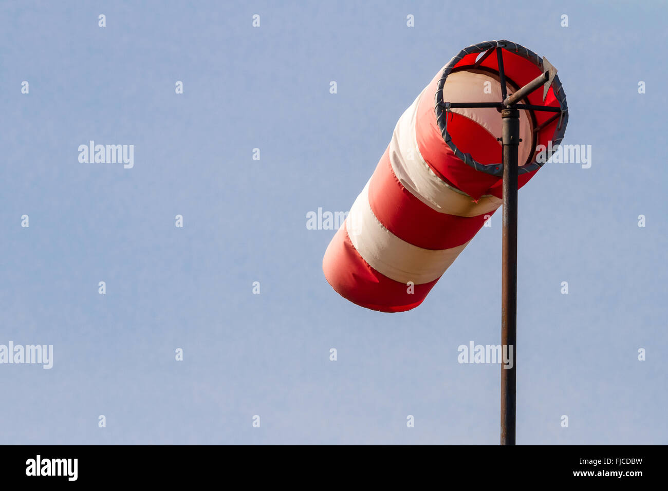 Frayed windsock in moderate wind against blue sky Stock Photo