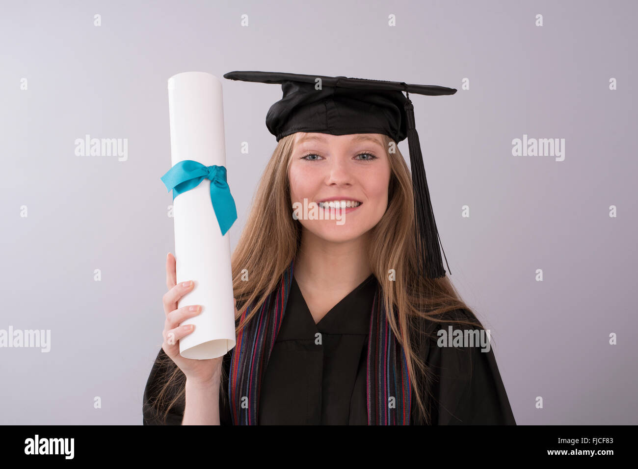 Young graduate in cap and gown with diploma Stock Photo